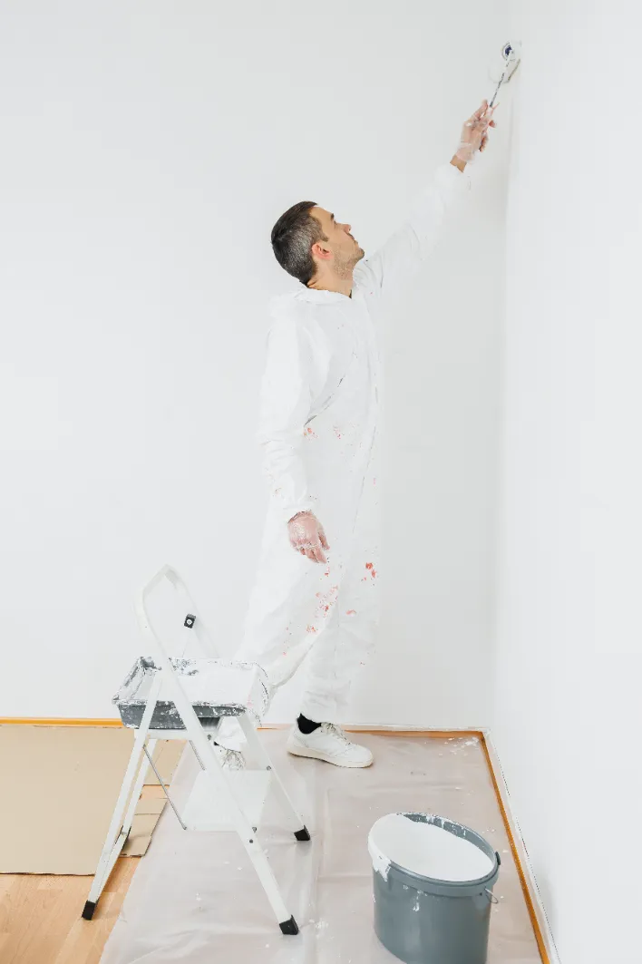 A man in overalls paints the walls.