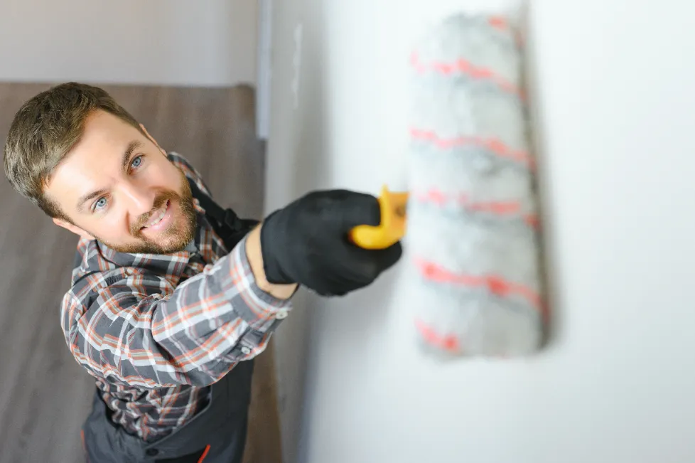 A painter painting the wall with a paint roller.