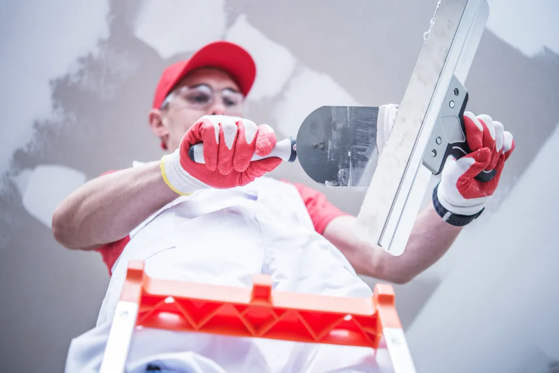 A man preparing the drywall patch on a trowel.