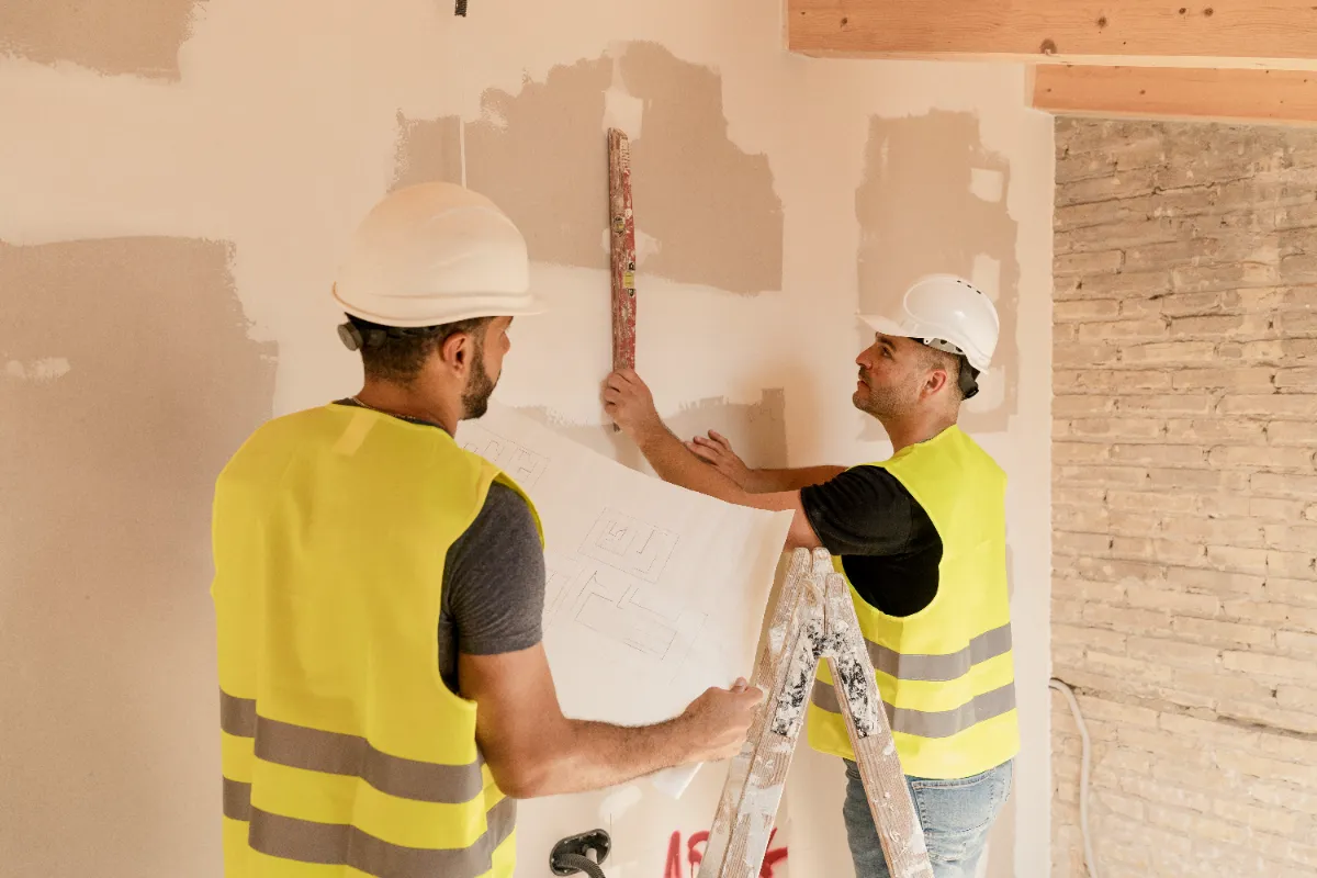 Two contractors working on how what to do on the wall of the clients house.