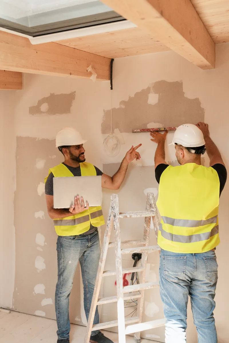 Two male contractors working on the drywall of the house.